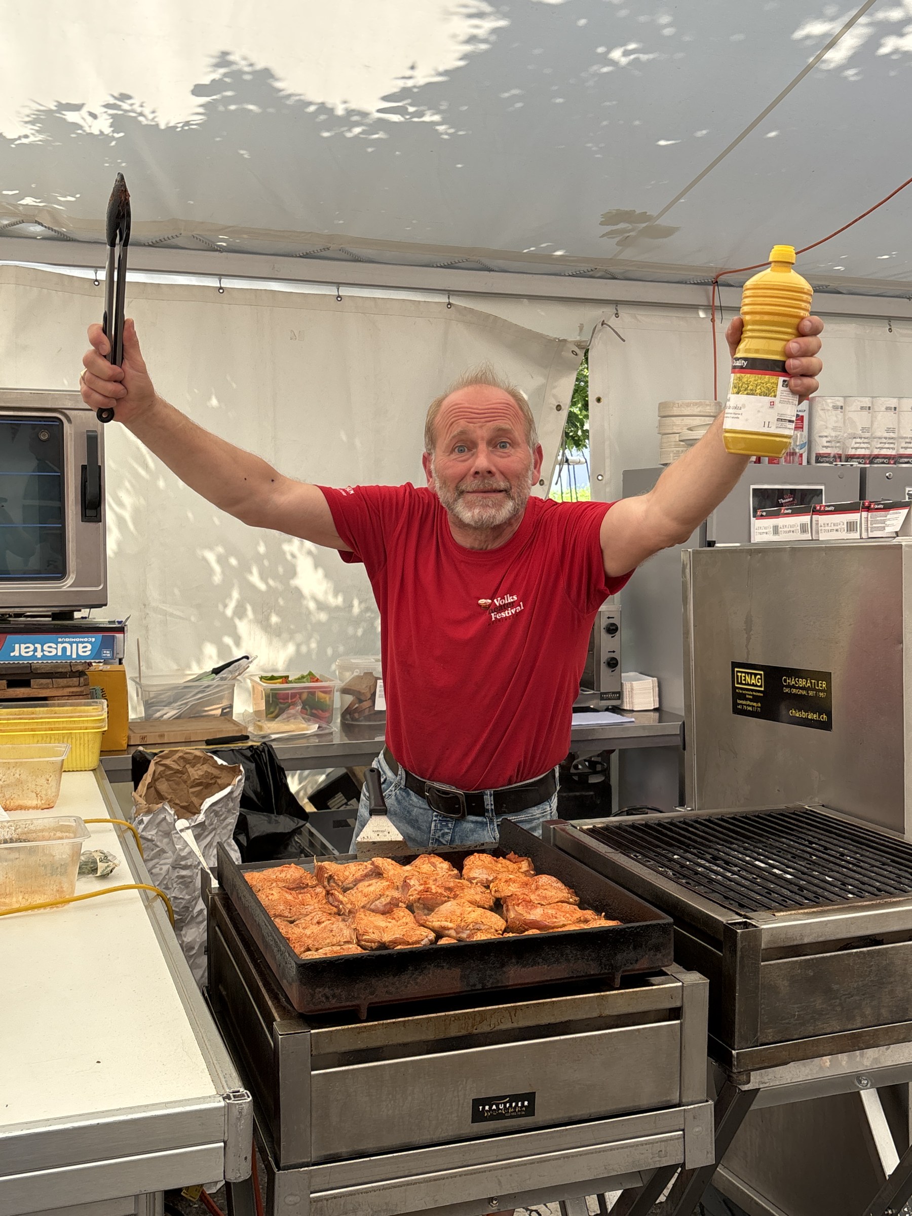 Volunteer in the red festival shirt at the grill in the festival tent